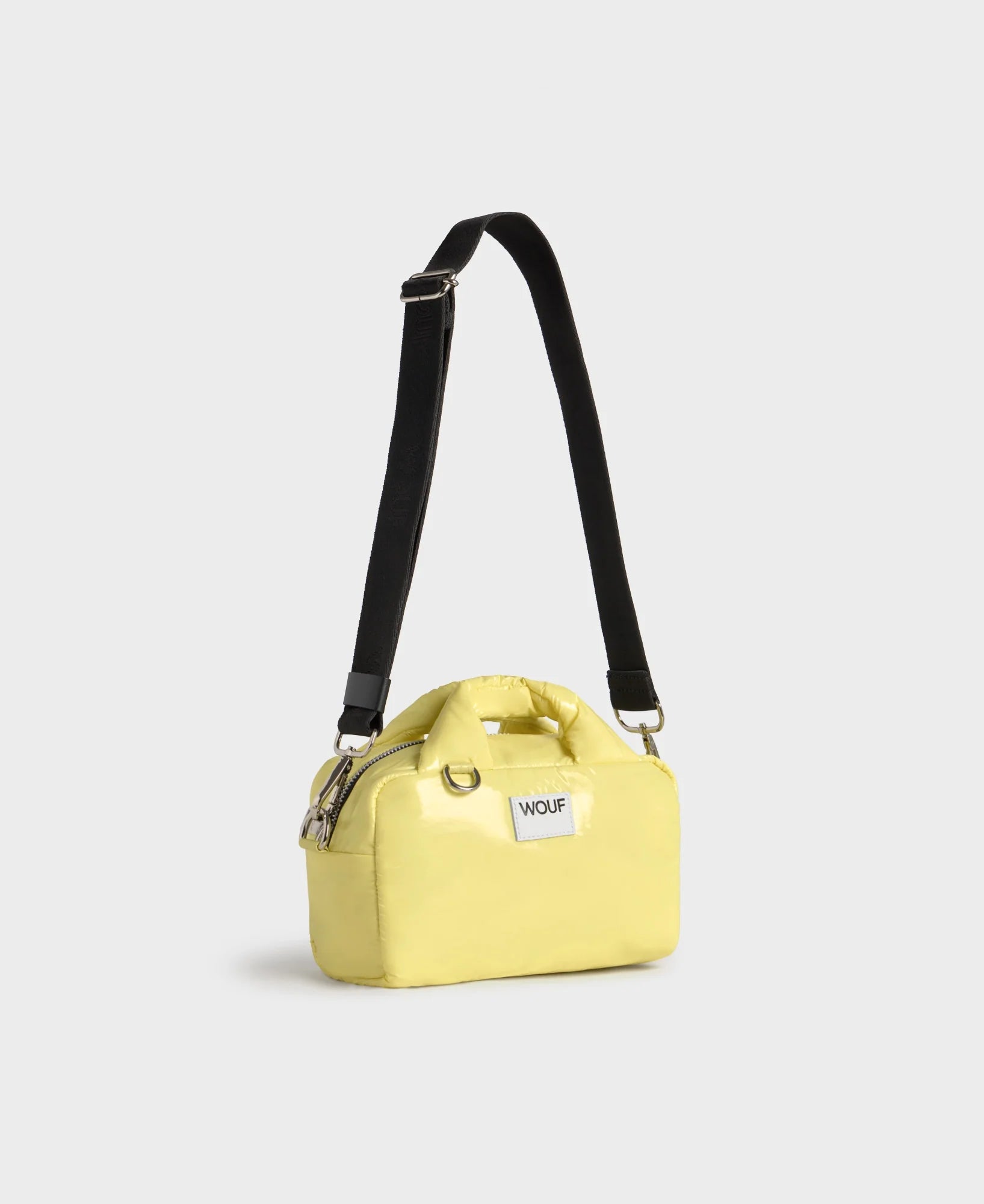 Yellow handbag with a black strap on a light gray background