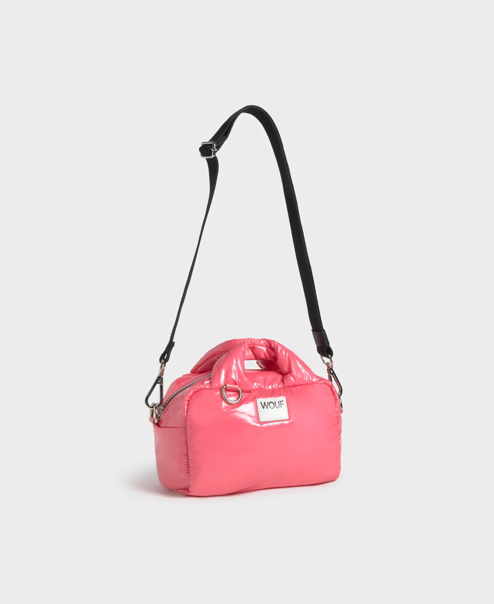 Pink bag with a black strap on a light gray background