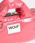 Close-up of a pink puffer bag with 'WOUF' brand label on a white background