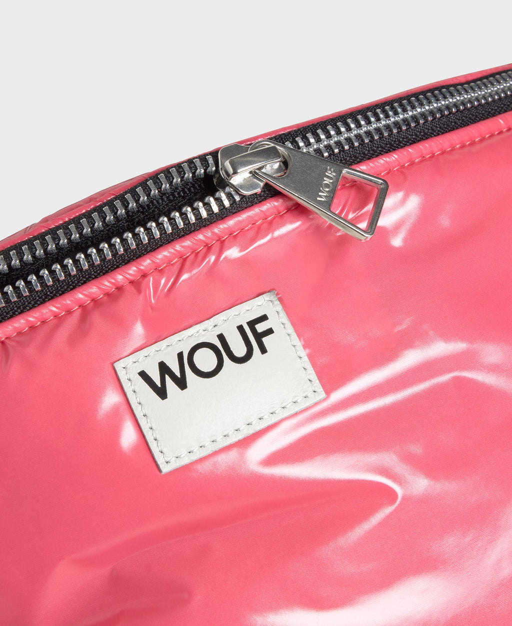 Close-up of a pink bag with a WOUF label on a white background
