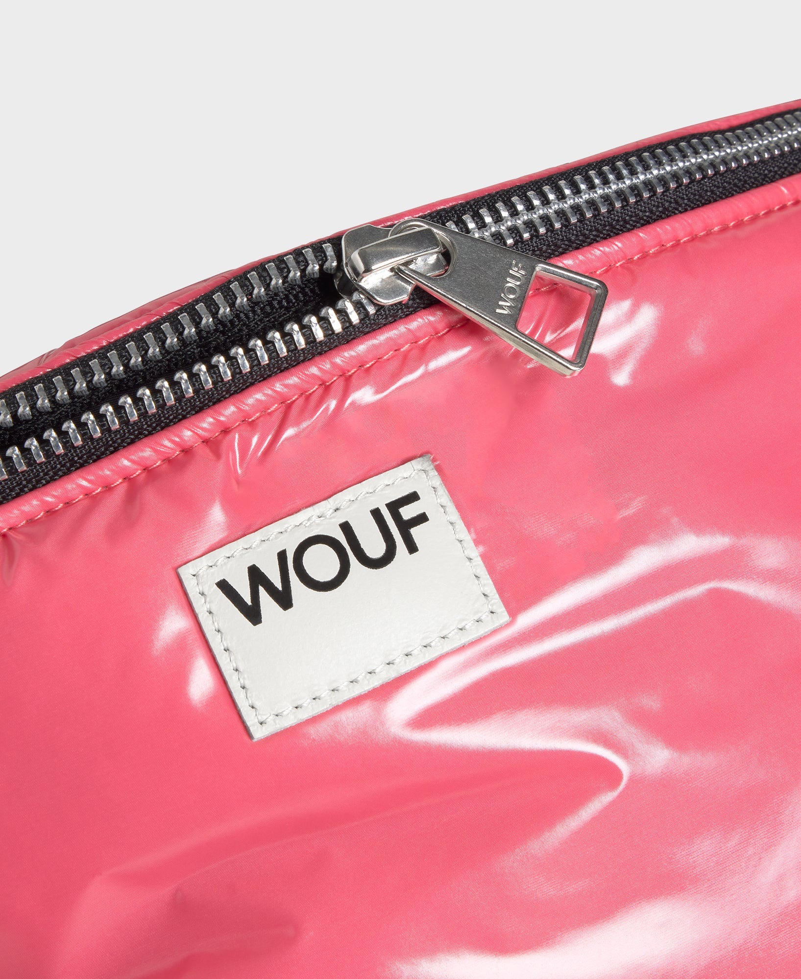 Close-up of a pink bag with a WOUF label on a white background