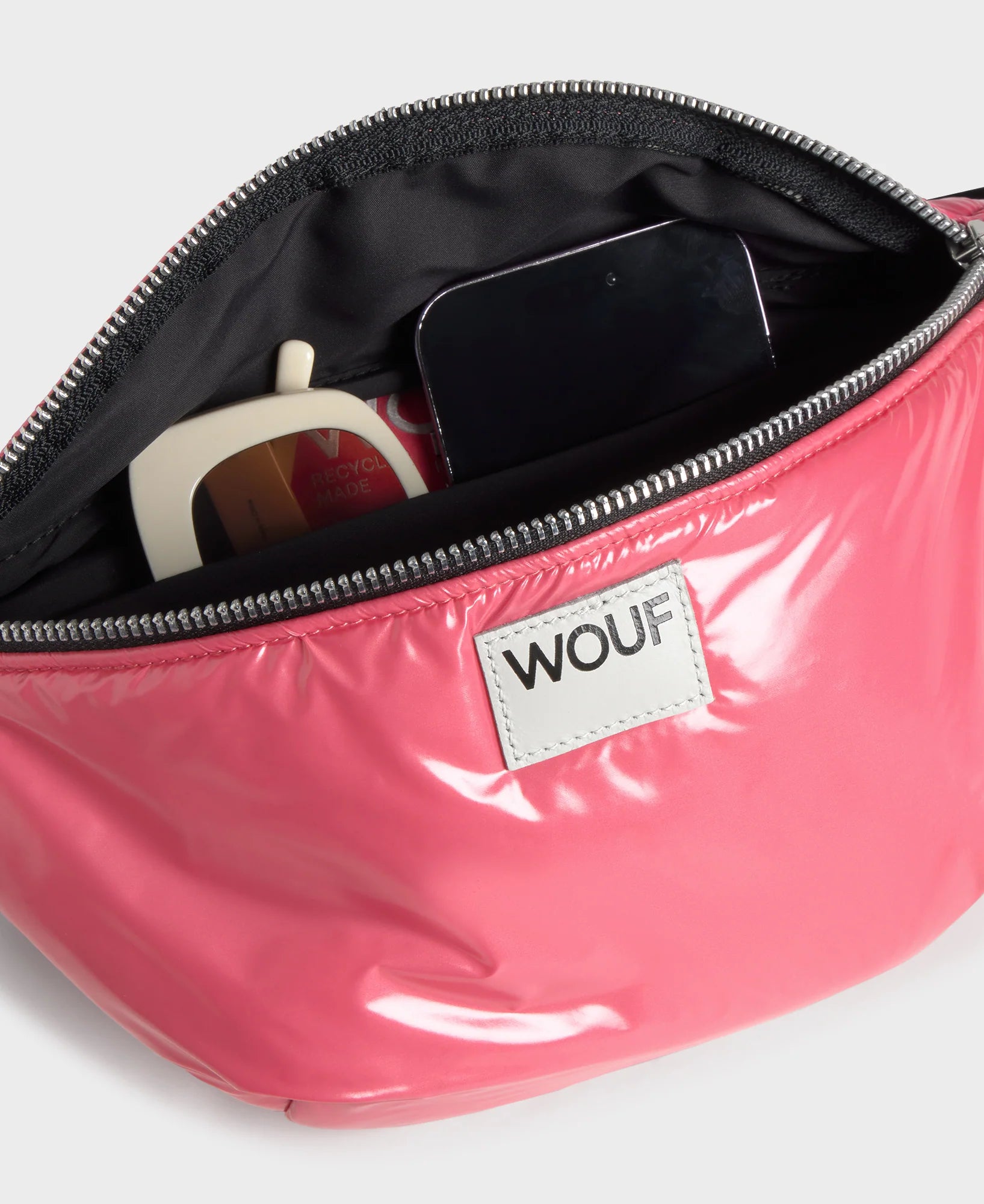 Pink pouch with a zipper, containing a phone and other items, on a white background.