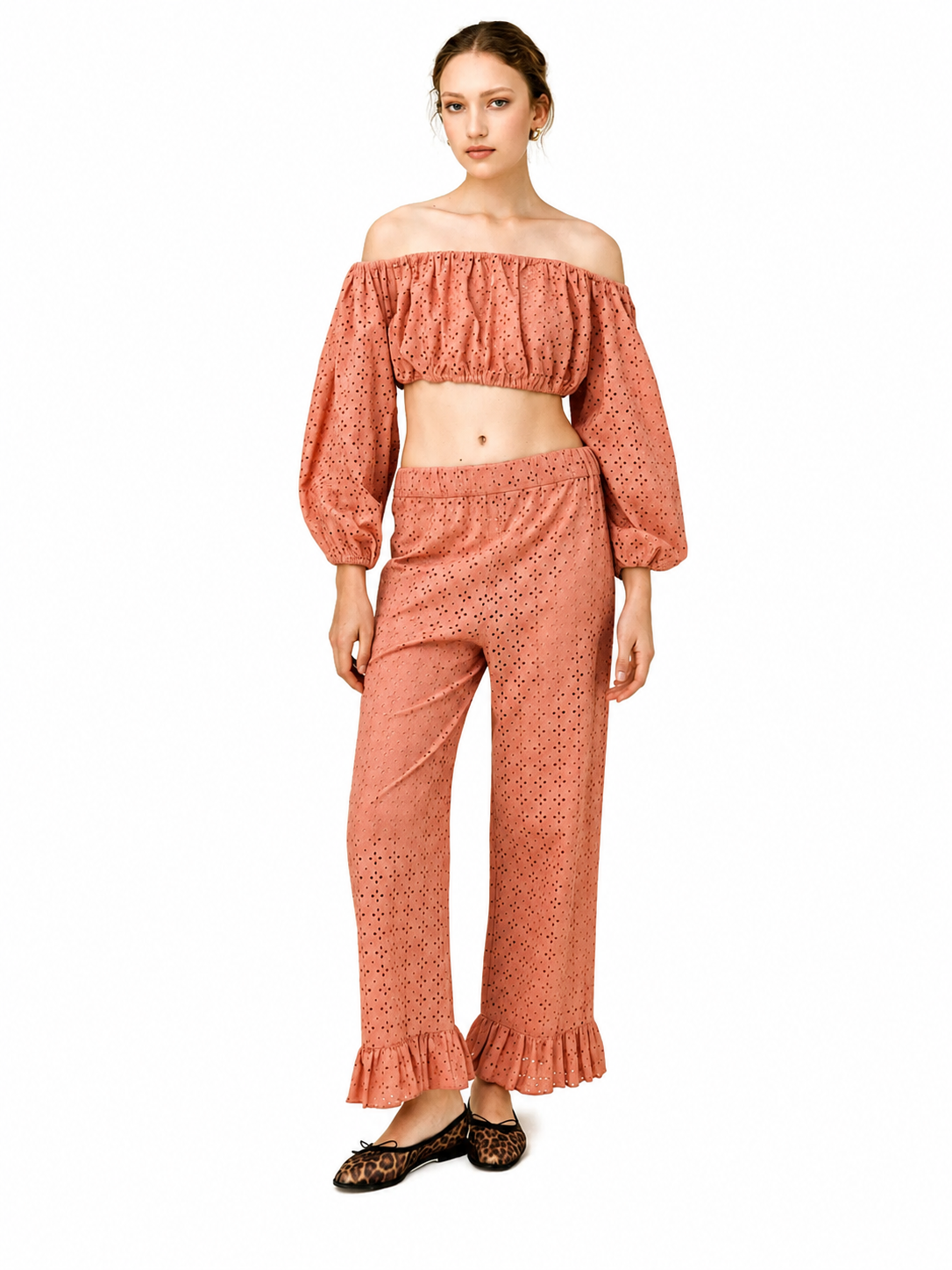 A model wearing a matching terracotta-colored two-piece set consisting of an off-the-shoulder long-sleeve crop top and high-waisted wide-leg pants with ruffled hems, paired with leopard-print flats, against a plain white background.