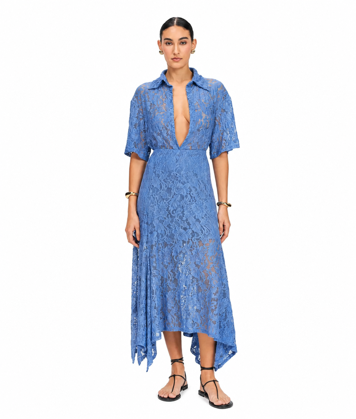 A woman modeling a blue lace midi dress with short sleeves, a deep V-neckline, and an asymmetrical hem, photographed against a plain white studio background.