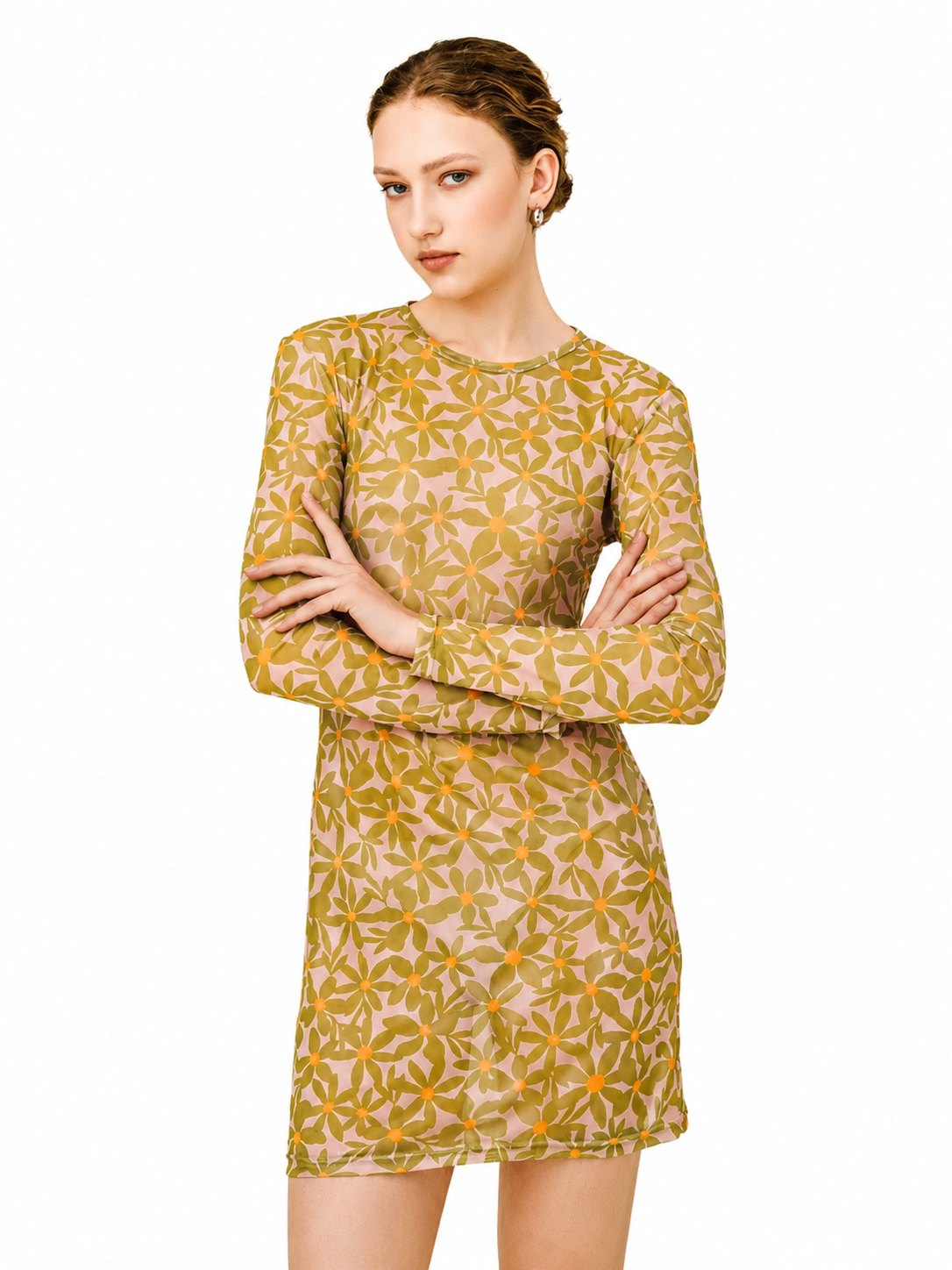 A woman modeling a long-sleeve mini dress with a retro floral pattern in mustard yellow and orange on a light beige background, set against a plain white studio backdrop.