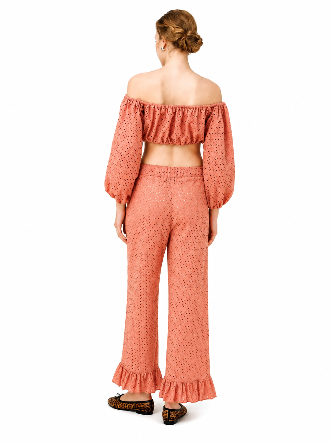 A woman shown from the back wearing a matching two-piece set consisting of an off-the-shoulder long-sleeve crop top and high-waisted wide-leg pants, both in a textured terracotta pink fabric. She is wearing leopard print flats against a solid white background.