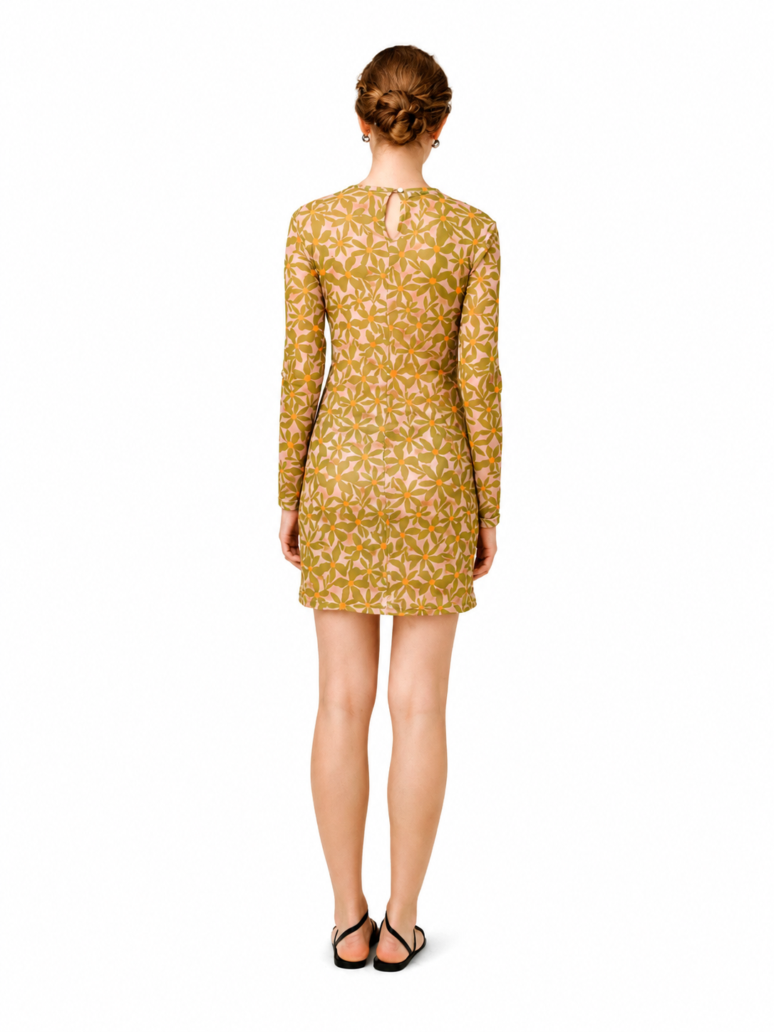 A woman viewed from the back wearing a long-sleeve mini dress with a mustard yellow and white geometric pattern, paired with black flat sandals, against a plain white background.