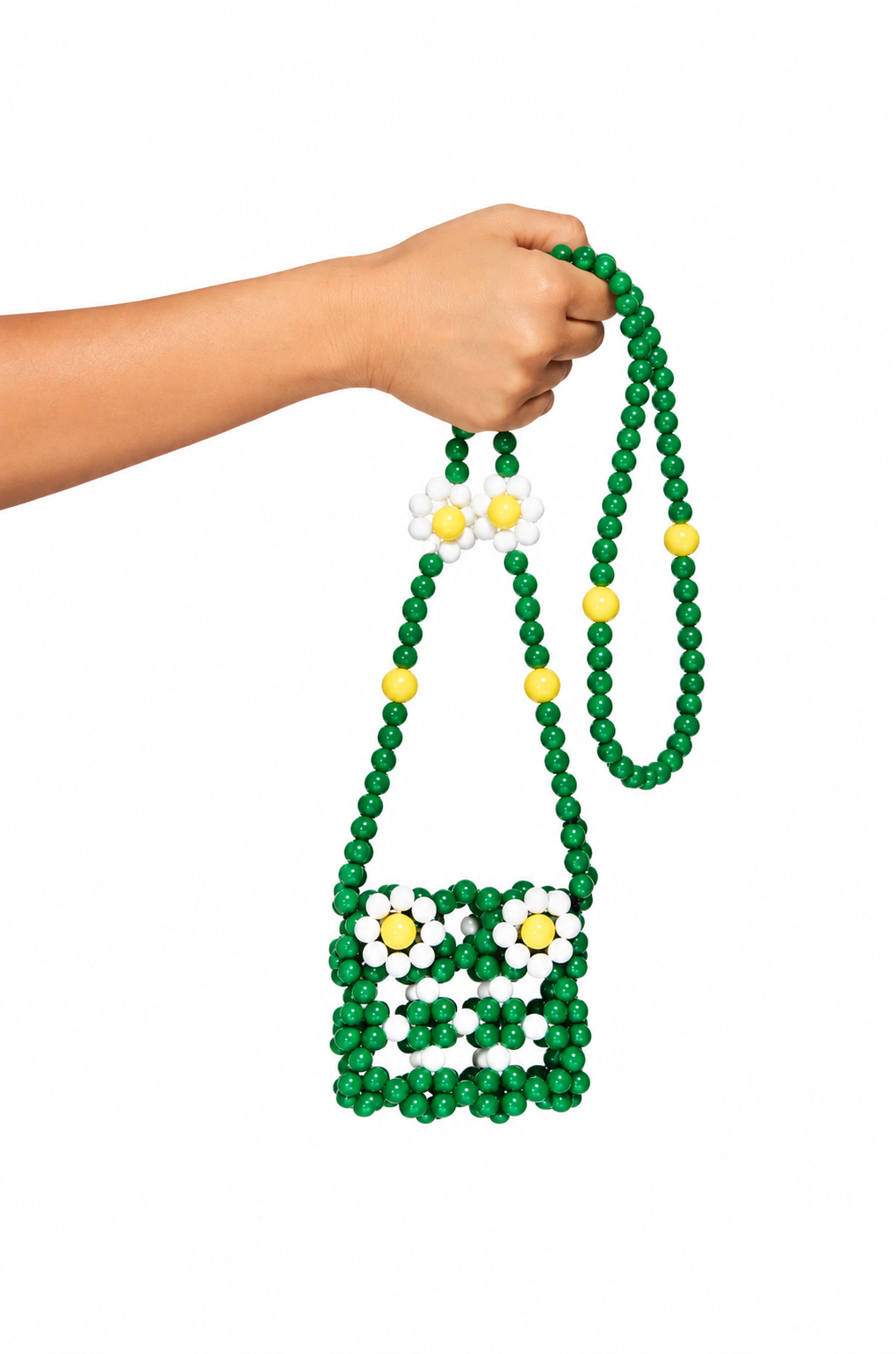 A hand holding a green beaded shoulder bag with white and yellow daisy flower details on a solid white background.