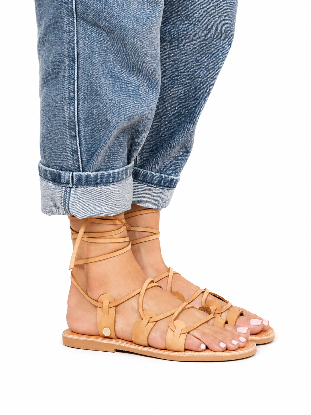 Sandalista Amazona tan leather lace-up sandals worn with cuffed blue jeans on white background