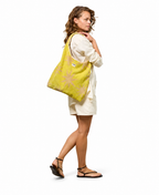 WOUF Fuerteventura T-Shirt Bag in yellow-green star print terry cloth worn on shoulder by model in white linen dress and black sandals