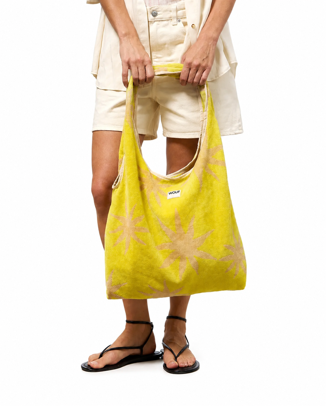 WOUF Fuerteventura T-Shirt Bag in yellow-green terry cloth with beige star print held by model wearing white shorts and black sandals