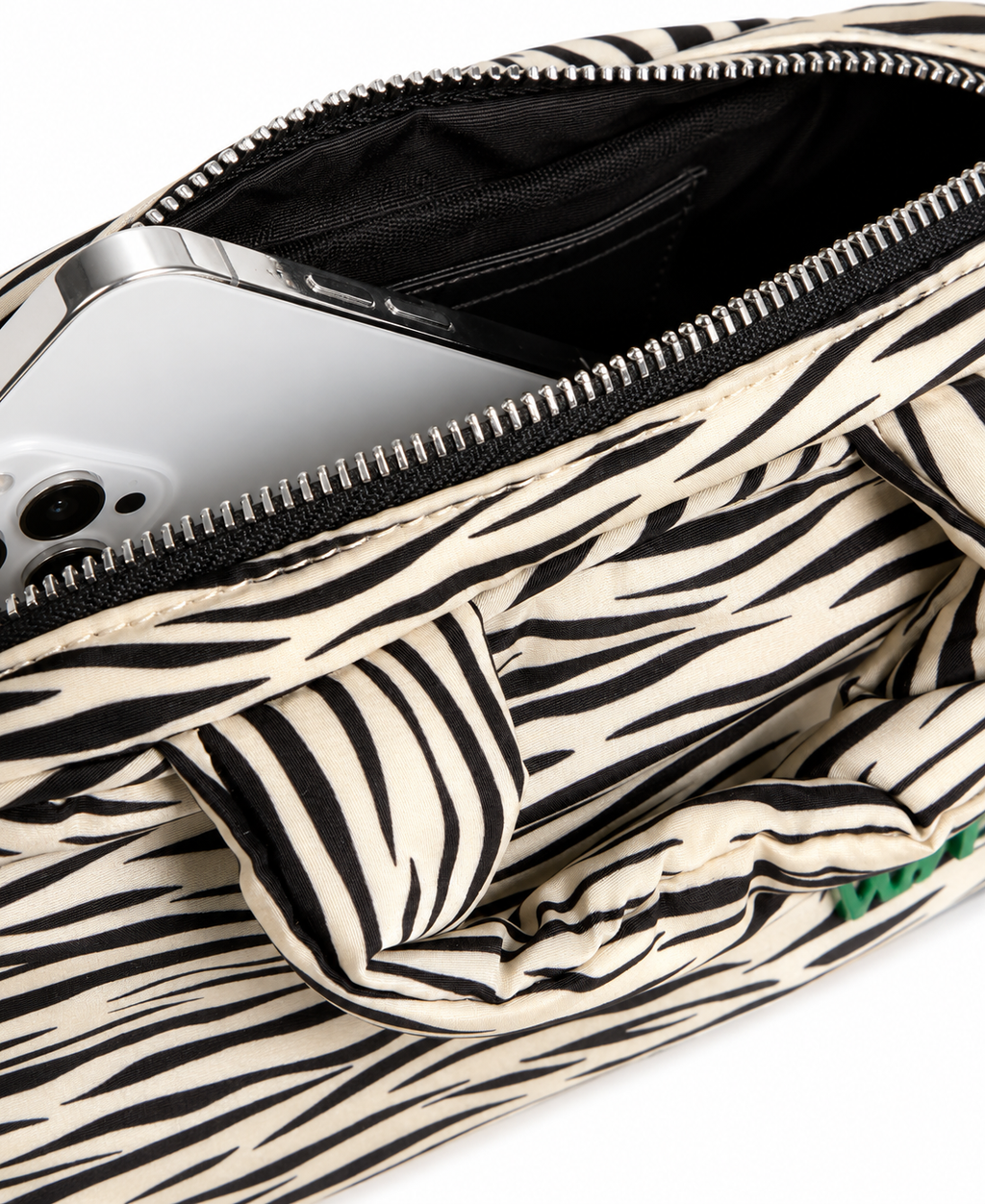 Close-up of a zebra-print fabric bag with an open zipper, showing a silver smartphone inside, on a white background.