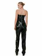 A woman shown from the back wearing a glossy black strapless corset-style top and matching high-waisted pants with a shiny patent-like finish, photographed against a plain white studio background.