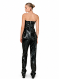 A model shown from the back wearing a glossy black strapless corset top and matching high-waisted patent pants against a plain white background.