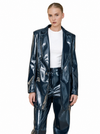 A model wearing a shiny dark blue faux leather blazer and matching pants over a white t-shirt, shot against a solid white background.
