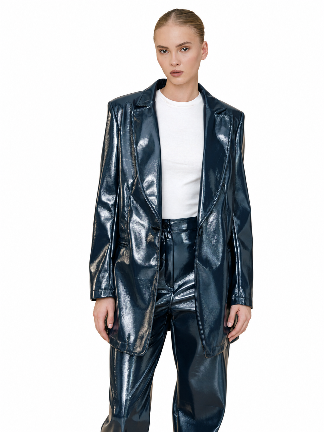 A model wearing a shiny dark blue faux leather blazer and matching pants over a white t-shirt, shot against a solid white background.
