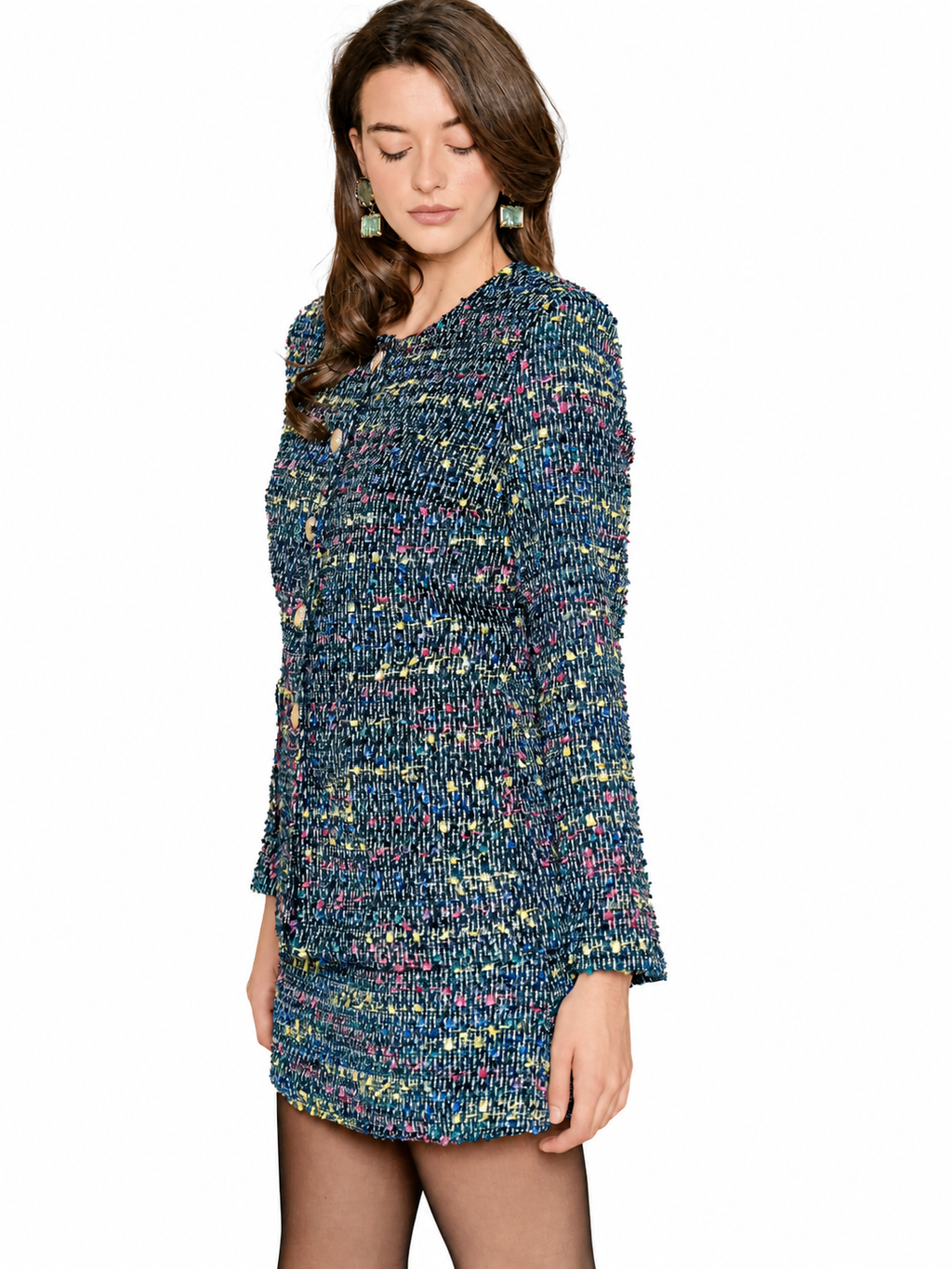 A woman wearing a textured tweed jacket with a multicolor pattern of blue, green, yellow, and pink threads, set against a plain white background.