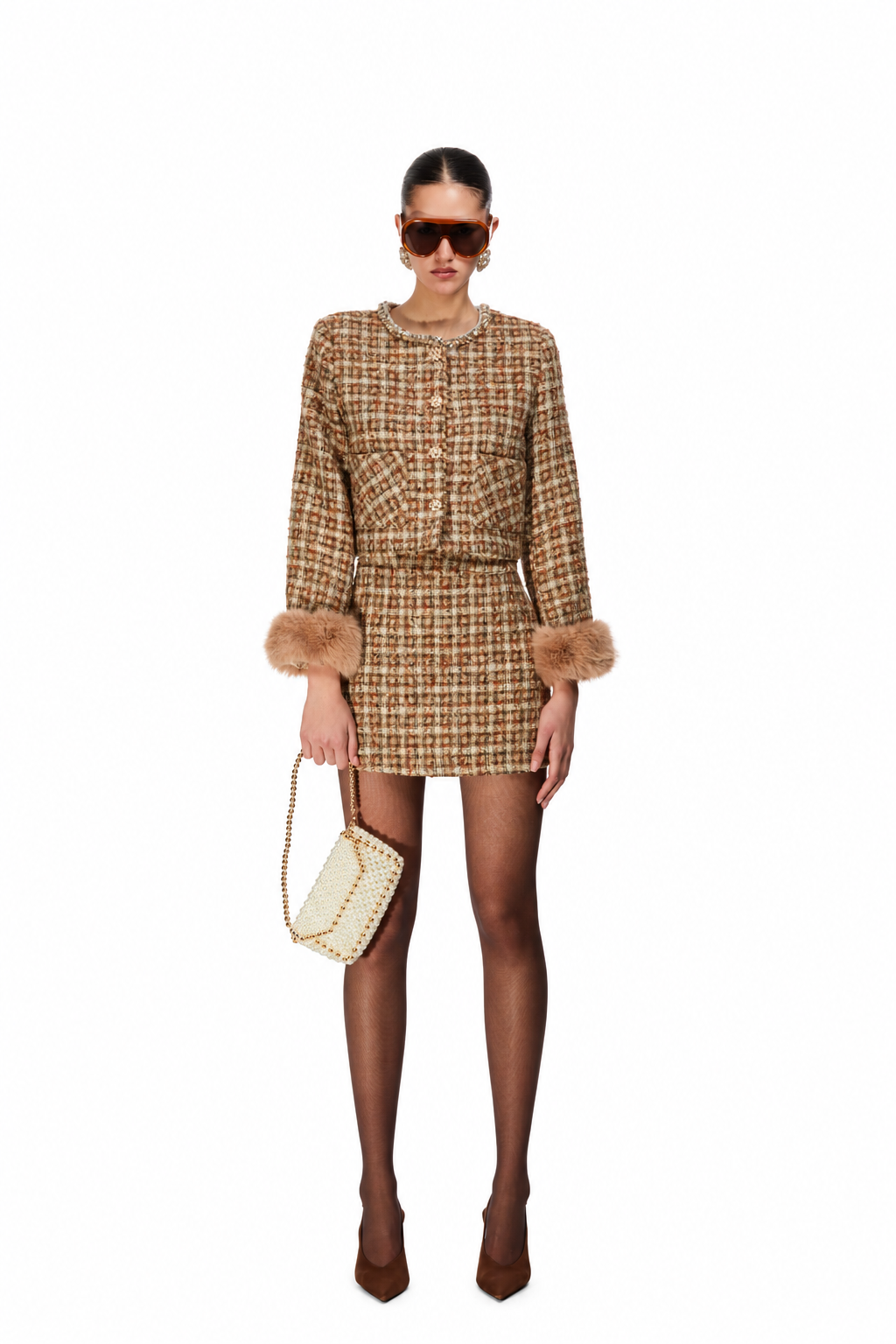 A model wearing a brown and beige tweed mini dress with faux fur trim at the cuffs, holding a matching tweed handbag, set against a plain white background.