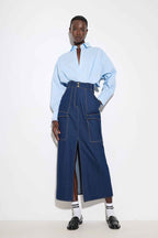 Person wearing a light blue shirt and blue denim jumpsuit on a white background