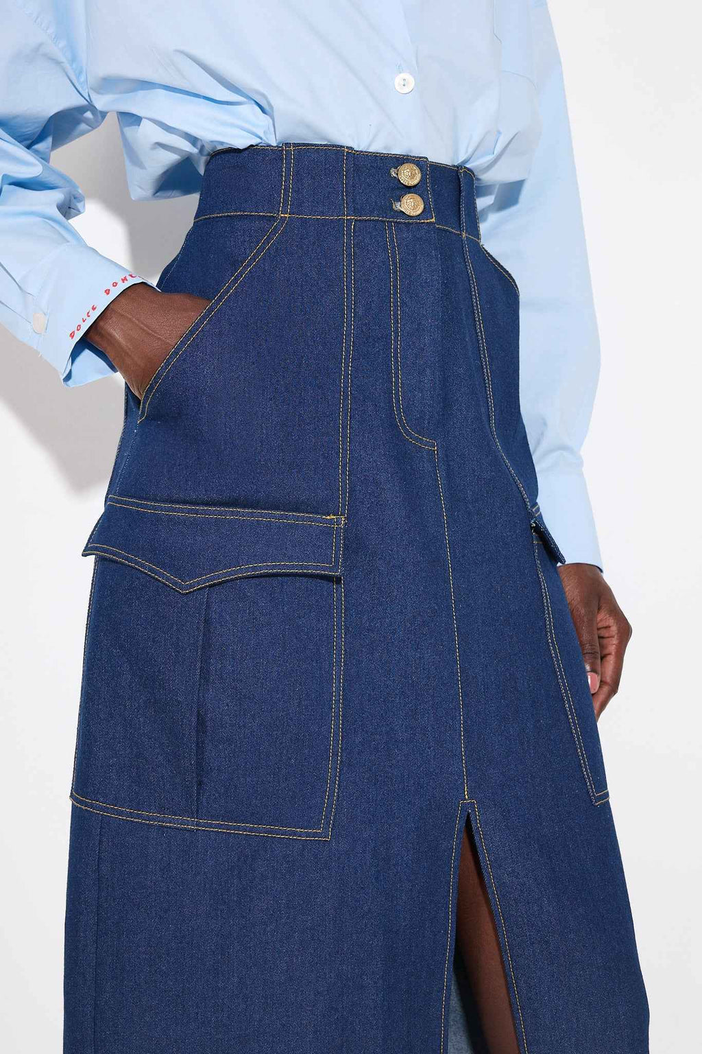 Person wearing a blue denim skirt with a plain background