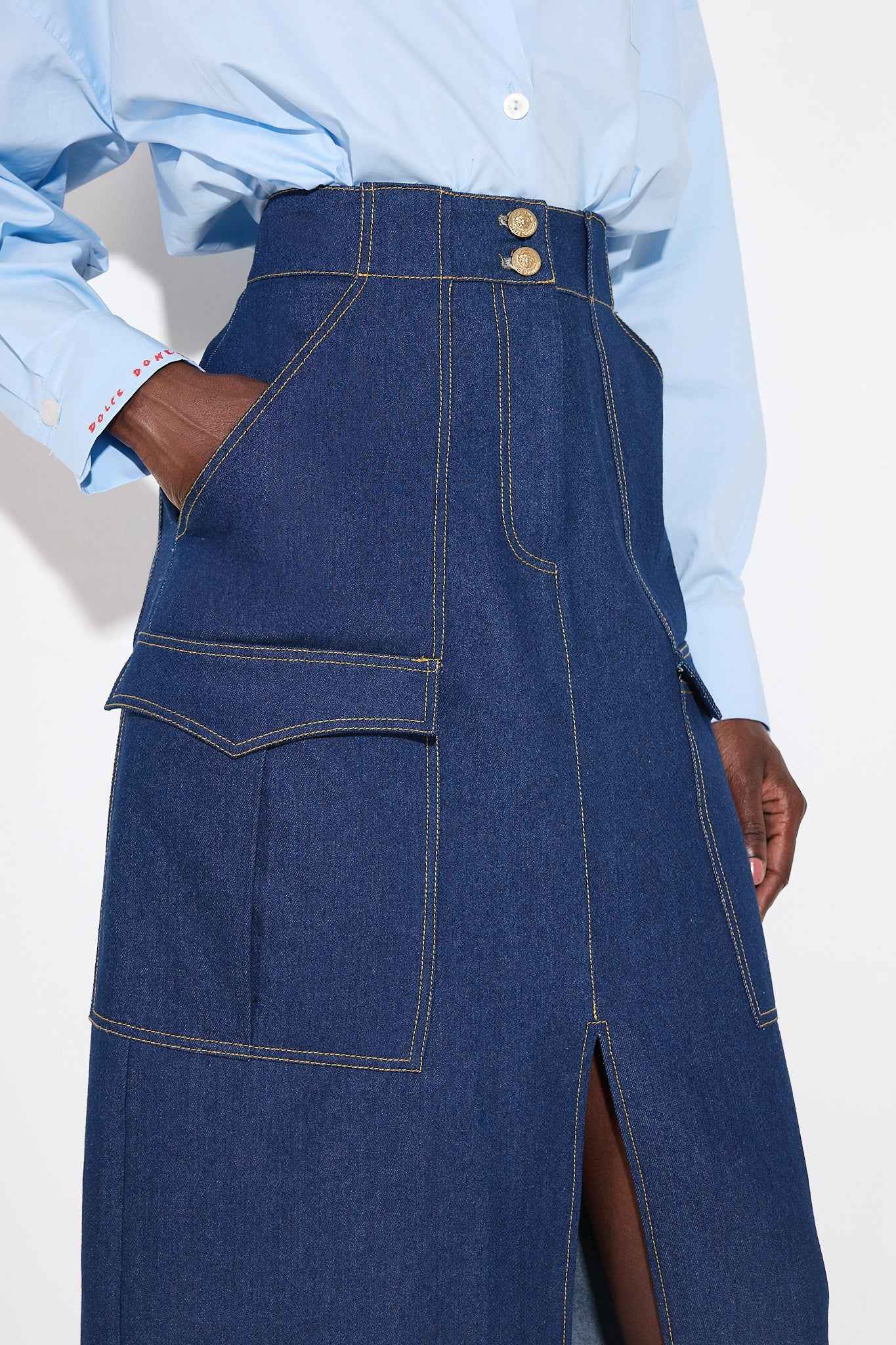 Person wearing a blue denim skirt with a plain background