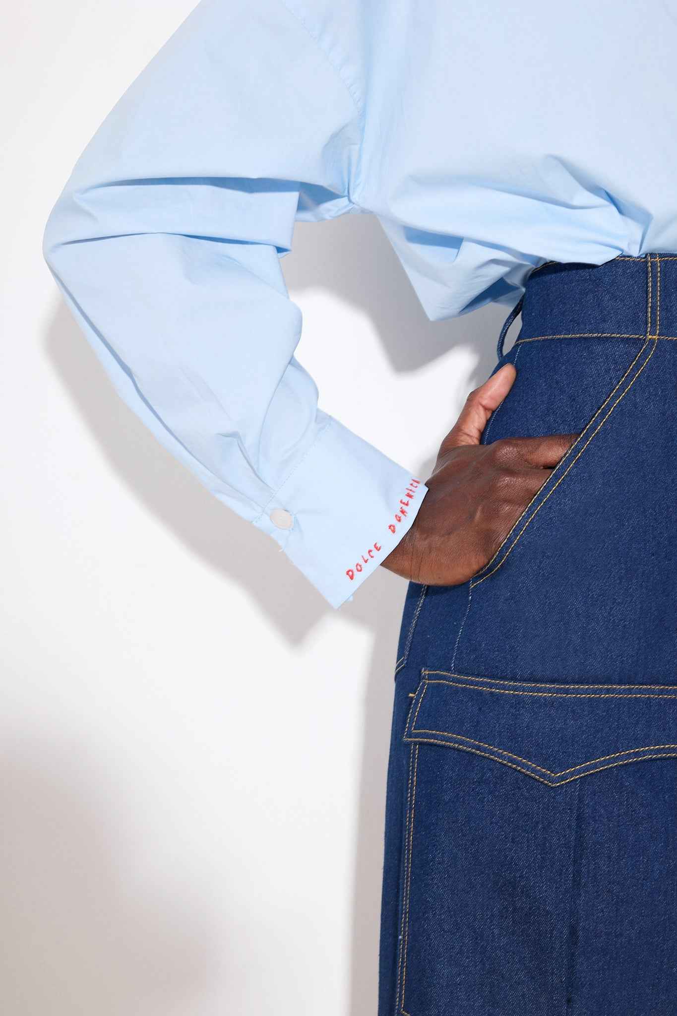 Blue denim skirt with a front slit on a white background