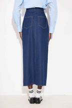 Person wearing a blue denim skirt with a light blue shirt on a white background