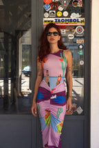 Woman wearing a colorful dress with a graphic design, standing in front of a door with stickers.