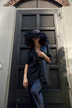 Person with a large black afro sitting against a dark wooden door.