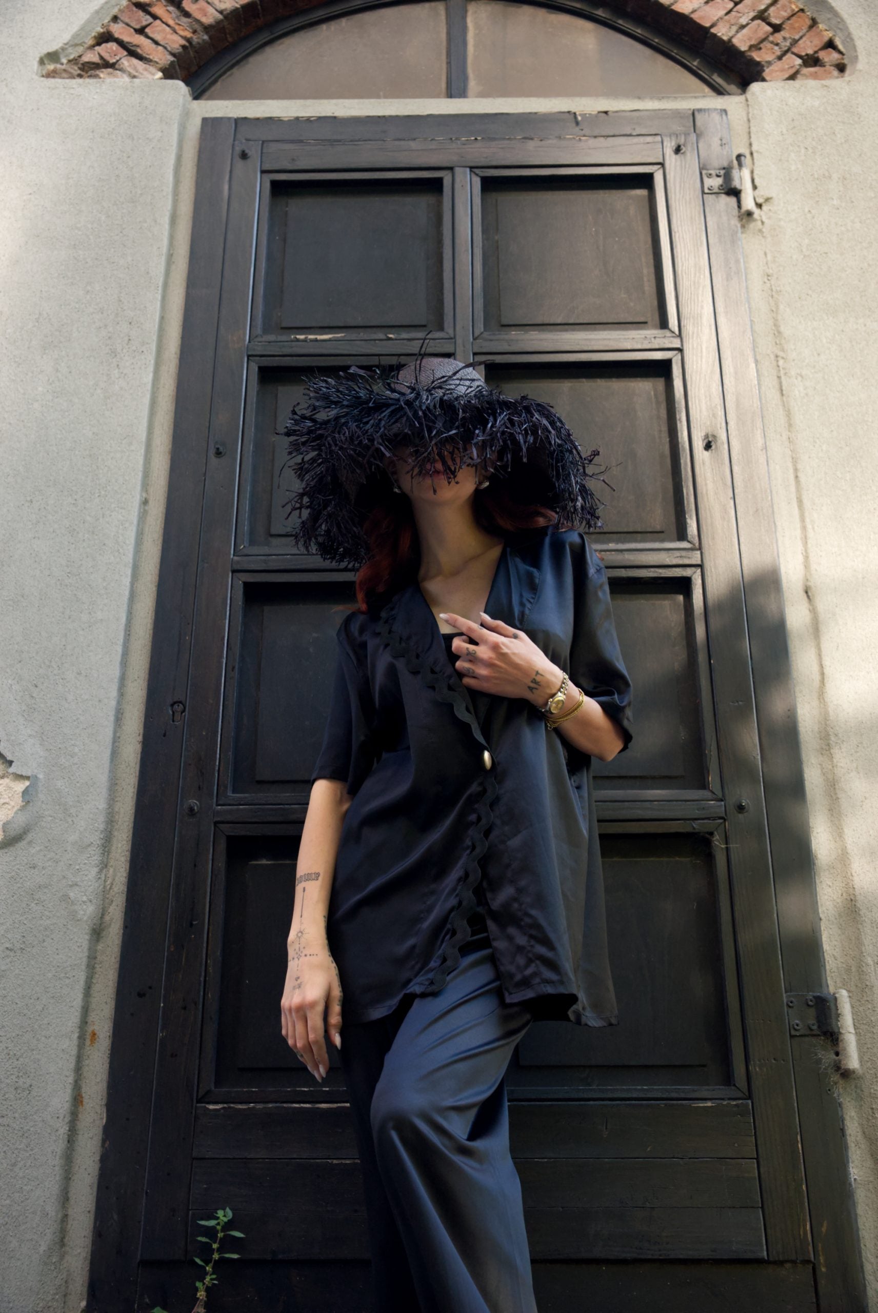 Person with a large black afro sitting against a dark wooden door.