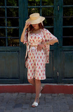 Woman in a patterned outfit standing in front of a dark green door.