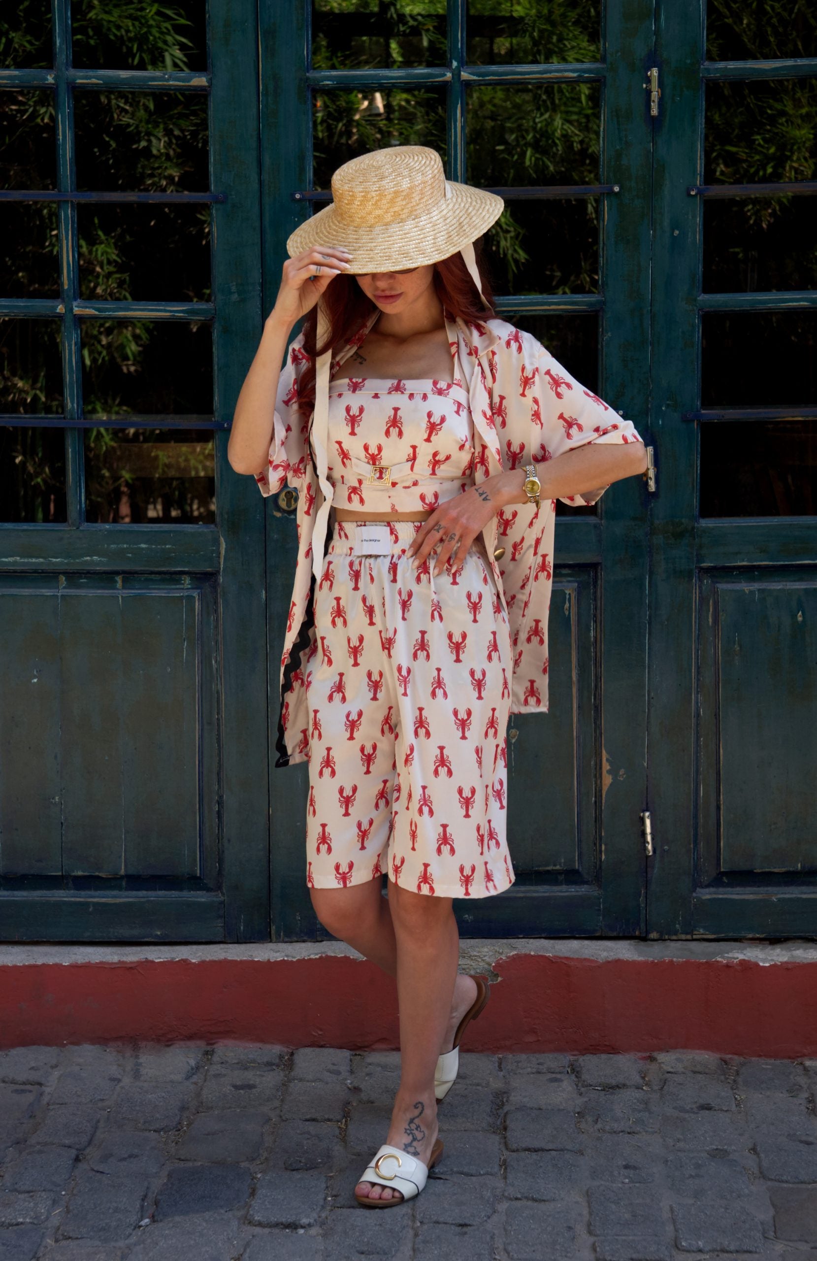 Woman in a patterned outfit standing in front of a dark green door.