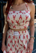 Person wearing a two-piece outfit with red lobster pattern on a white background