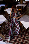Woman in a striped outfit sitting in a restaurant with patterned floor and tables.