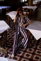 Woman in a striped outfit sitting in a restaurant with patterned floor and tables.