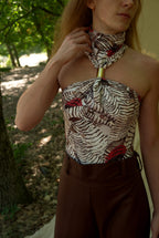 Woman wearing a patterned top and brown pants outdoors
