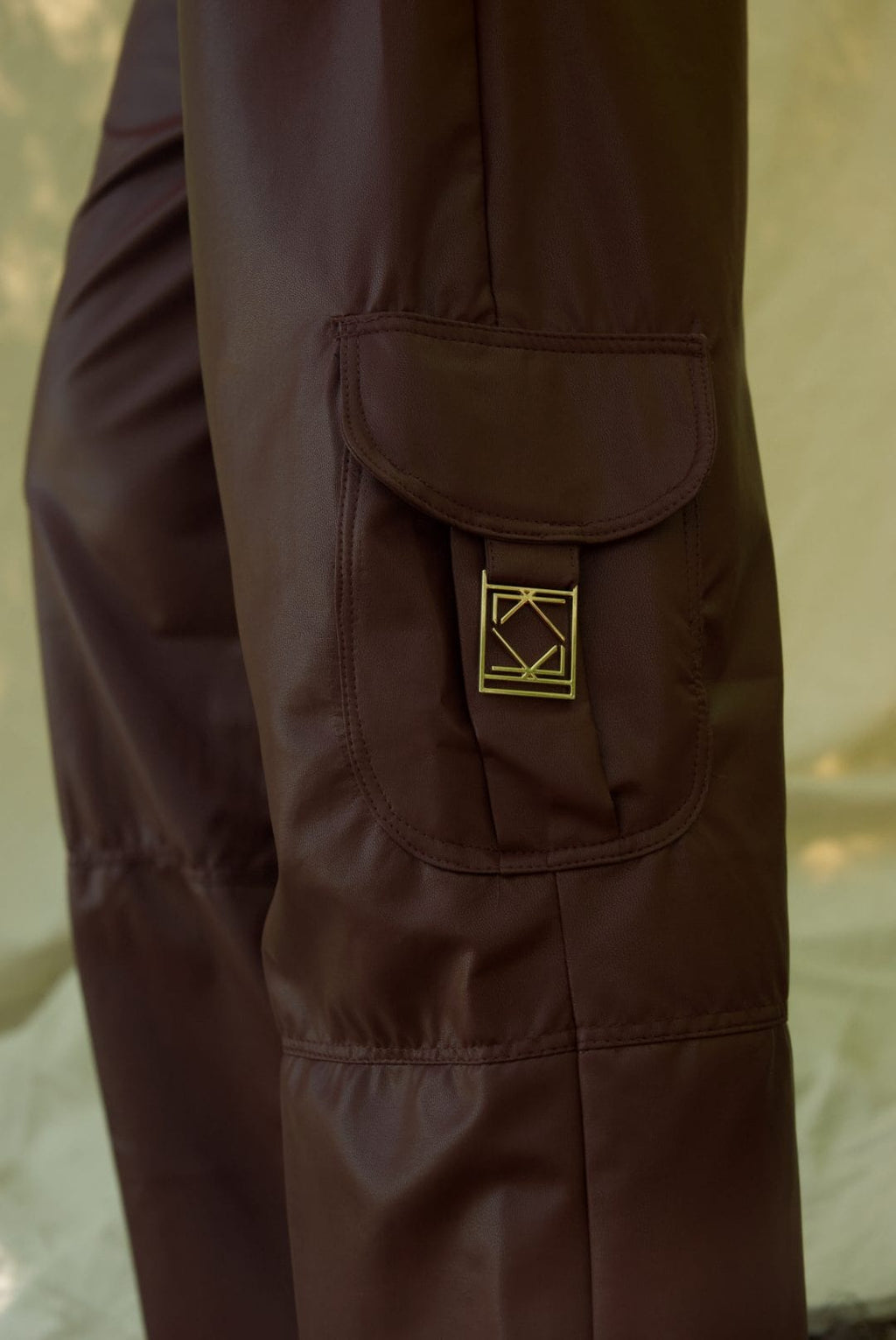 Brown jacket with a gold patch on a neutral background