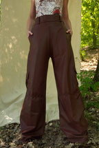 Person wearing brown wide-leg pants standing outdoors with a natural background