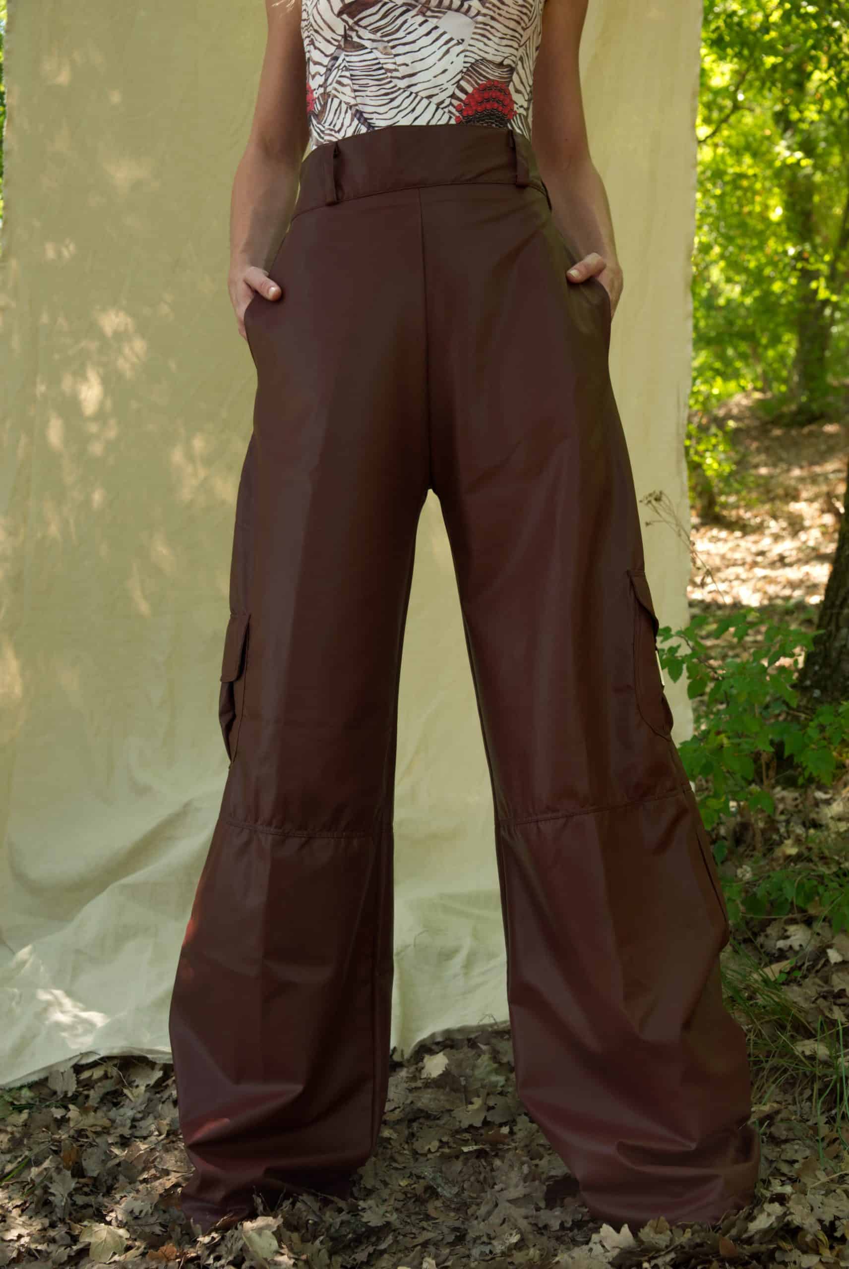 Person wearing brown wide-leg pants standing outdoors with a natural background