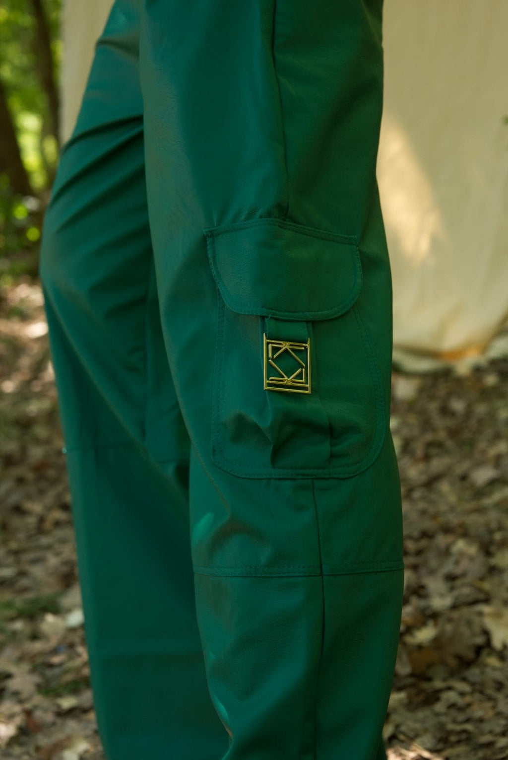 Green pants with a logo patch on a blurred natural background