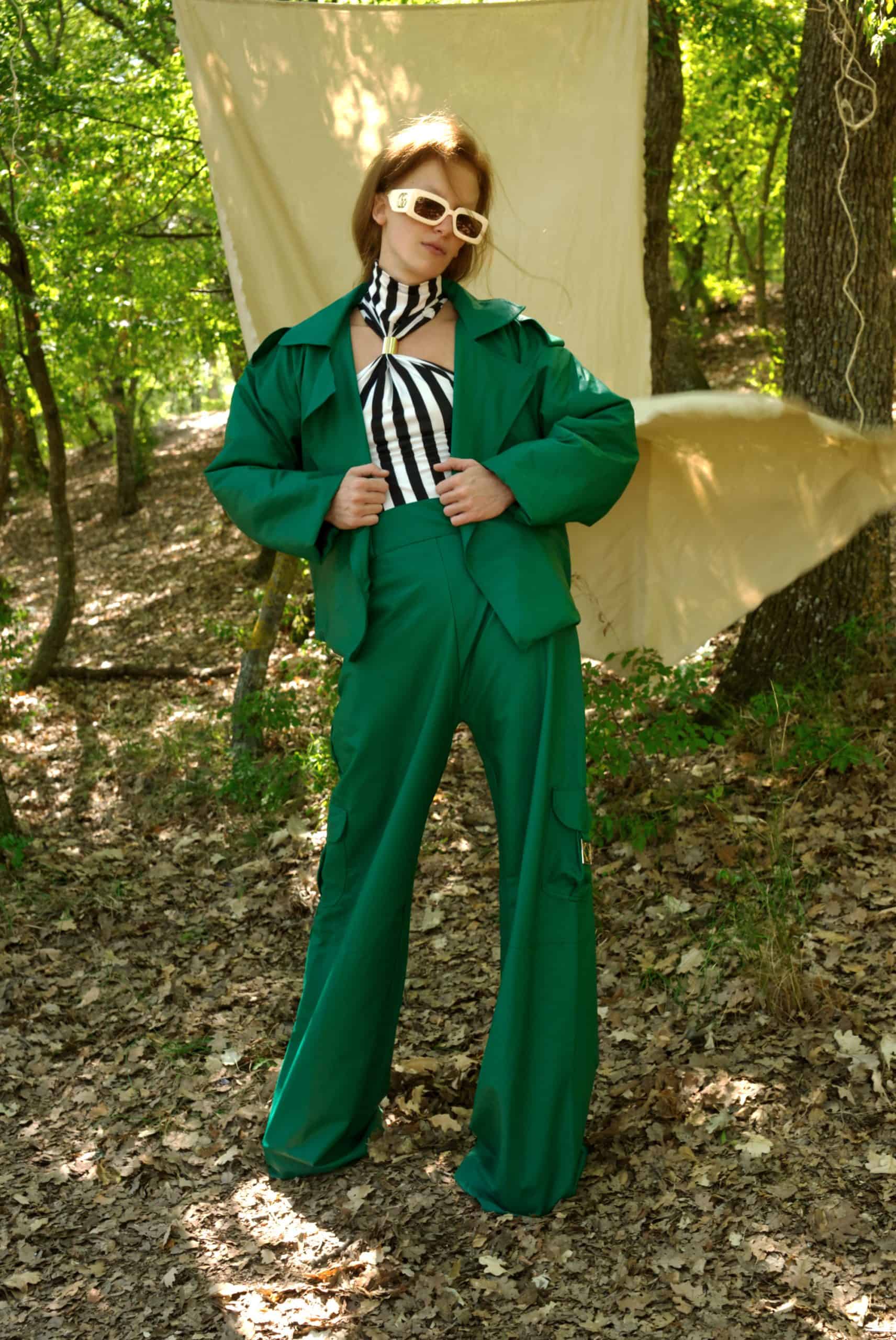 Person wearing a green suit with a black and white striped tie in a forest setting