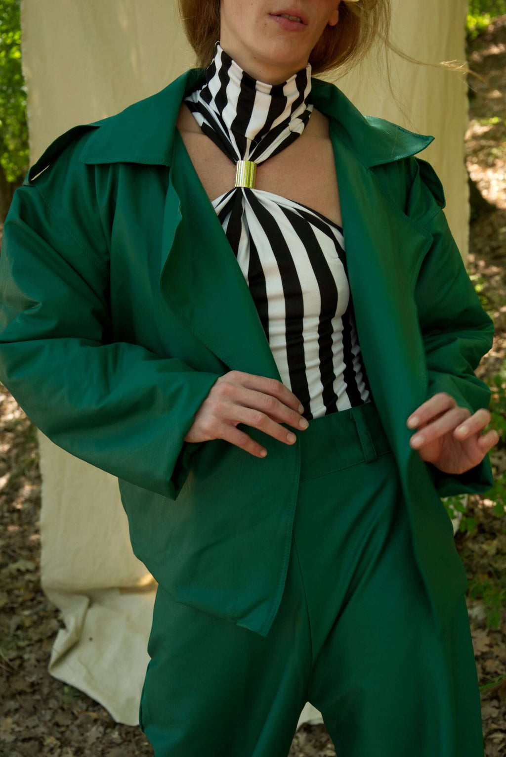 Person wearing a green coat over a black and white striped outfit with a zebra print scarf.