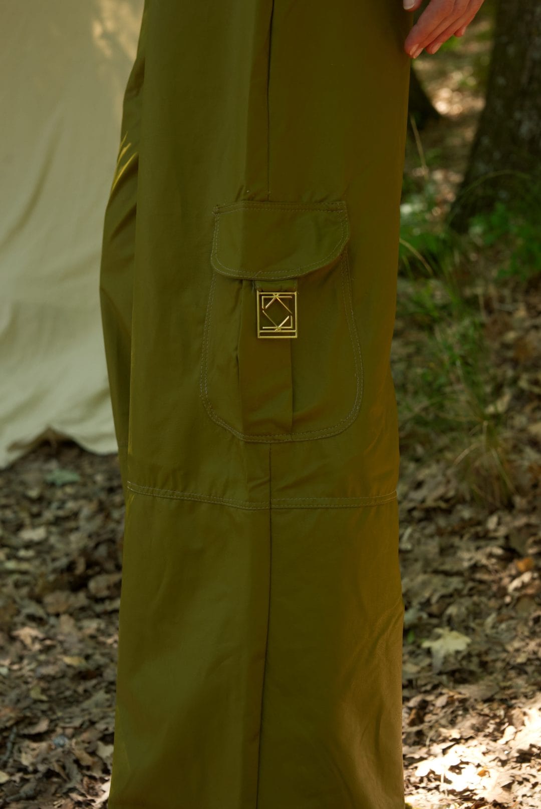 Green pants with a logo on a person standing in a forest setting