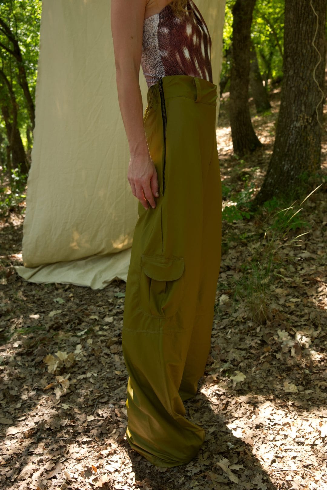 Person wearing a long, green skirt standing in a forest setting.