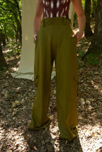 Person wearing green wide-leg pants in a forest setting