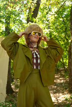 Person in a green outfit with sunglasses in a forest setting