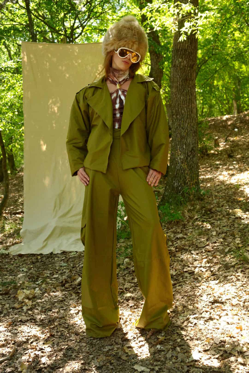 Person wearing a green trench coat and pants in a forest setting