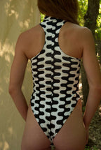 Person wearing a black and white patterned swimsuit in a natural setting
