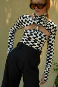 Person wearing a black and white patterned top with cut-out design and sunglasses.