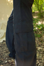 Dark pants worn by a person in a natural outdoor setting with greenery.